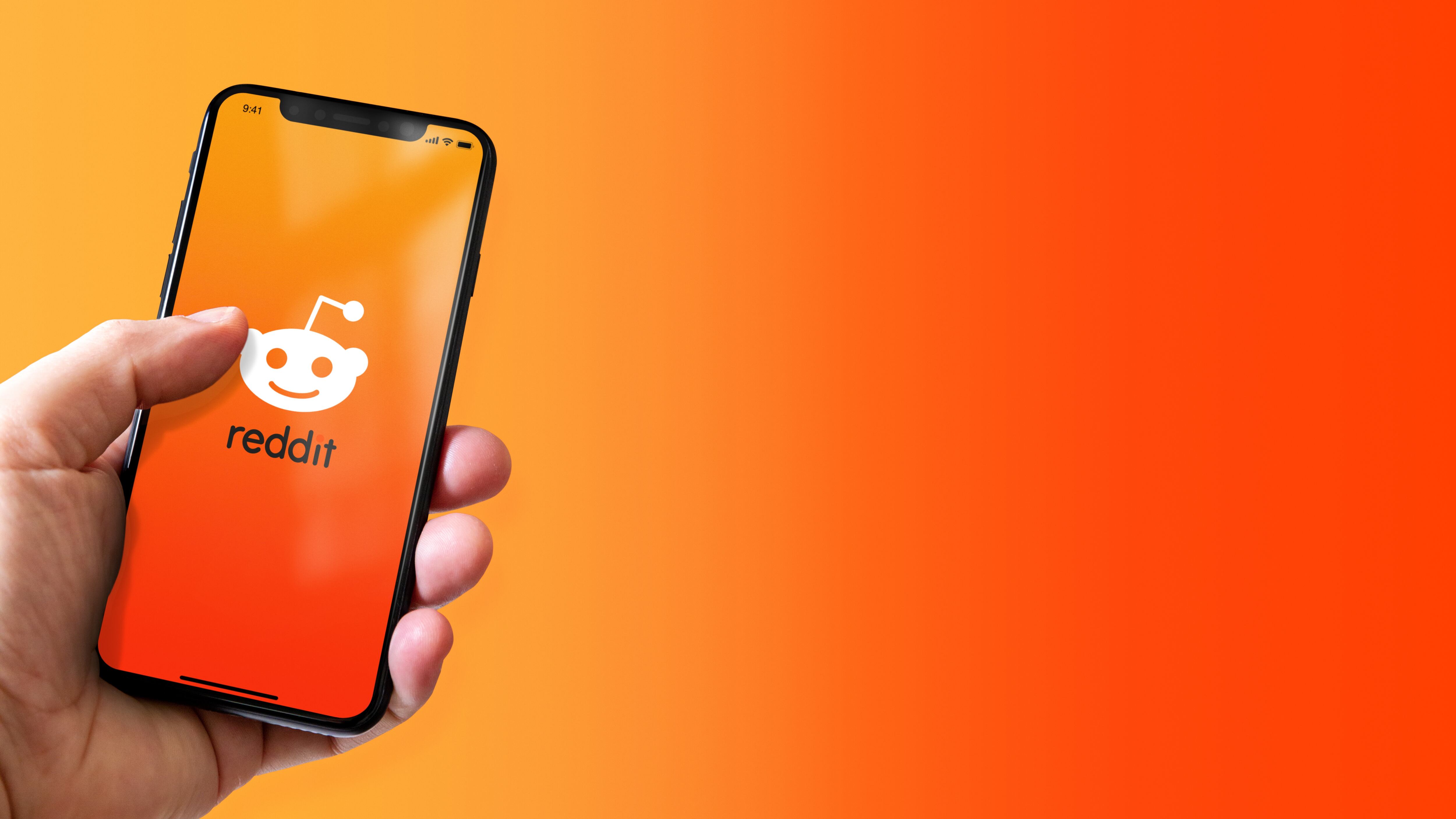 Hand holding iphone smartphone with Reddit logo. Horizontal banner